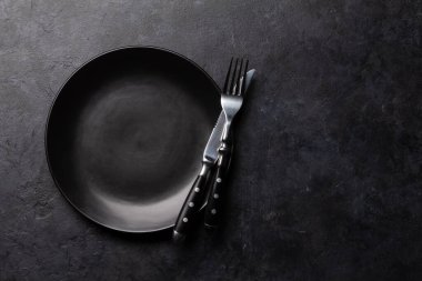 Boş tabak ve gümüş takımlar taş masaya. Üst görünüm düzlüğü kopyalama alanı ile yatıyordu. Yemek için şablon ya da maket