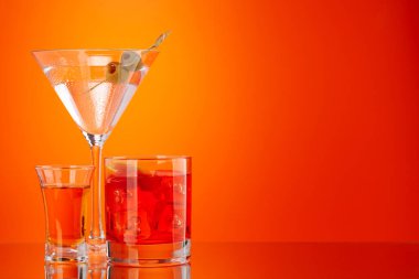 Shot ve negroni ve martini kokteyli turuncu arka planda.