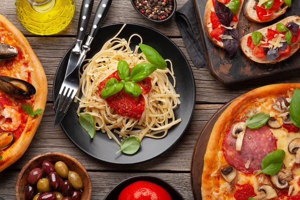 Italian cuisine. Pasta, pizza, olives and antipasto toasts. Flat lay on wooden table