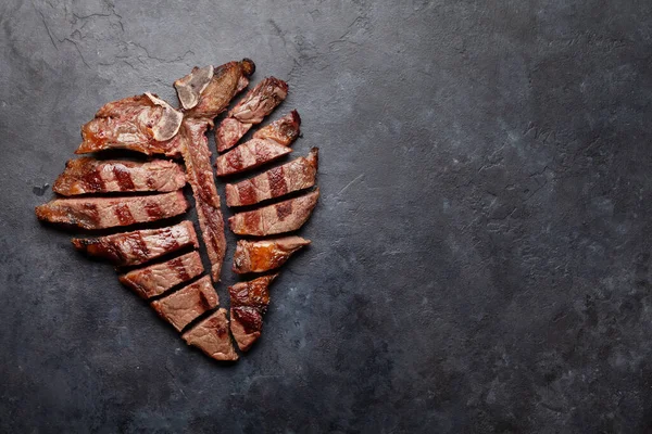 焼き肉のポーターハウスビーフステーキ ハーブやスパイスとスライスTボーン コピースペース付きのトップビューフラットレイ — ストック写真