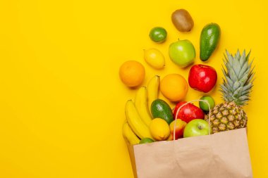 Sarı arka planda sağlıklı meyvelerle dolu bir poşet. Kopyalama alanı olan düz