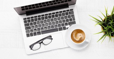 Laptop bilgisayarı, kahve ve malzemelerle dolu ofis masası. Üst Manzara. Düz yatıyordu