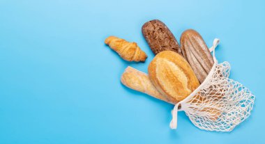 Mavi arka planda örgü içinde taze pişmiş ekmek. Kopyalama alanı olan düz