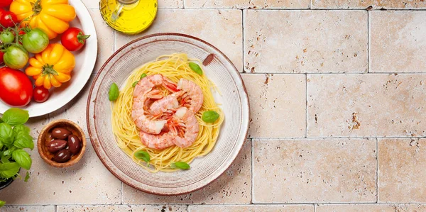 Pasta with shrimps and various garden tomatoes. Italian cuisine. Flat lay with copy space