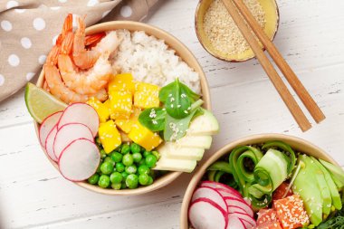Poke bowls with shrimps, salmon, avocado and mango. Traditional hawaiian meal. Top view flat lay clipart