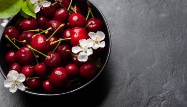 Kiraz çiçekleriyle dolu bir kasede olgunlaşmış kiraz. Üst görünüm düzlüğü kopyalama alanı ile yatıyordu
