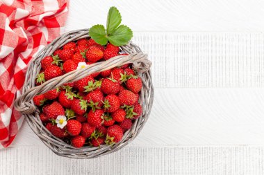 Tahta masadaki sepetin içinde olgun çilekler. Üst görünüm düzlüğü kopyalama alanı ile yatıyordu