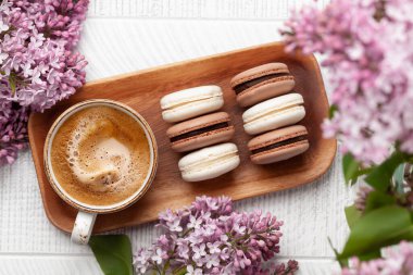 Kurabiye ve kahve. Üzerinde leylak çiçekleri olan ahşap bir masada. Üst görünüm düzlüğü