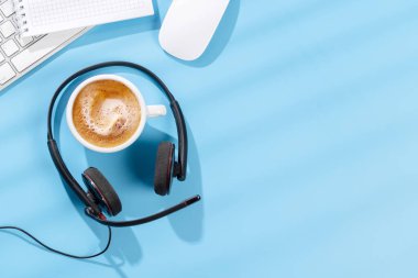 Kulaklık, ofis malzemeleri ve kahve ile üst düzey ofis masası. Güneşli ışıklı çalışma alanı ve kopyalama alanı