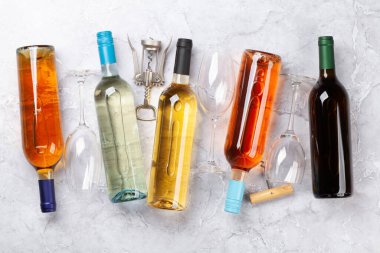 Taş masada çeşitli şarap şişeleri ve tirbuşon var. Düz yatıyordu