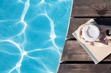Yüzme havuzunun yanında kitap ve kahve. Yaz tatili. Düz yatıyordu