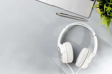 Bilgisayarı, ofis malzemeleri ve kulaklıkları olan üst düzey ofis masası. Güneşli ışıklandırmalı düz çalışma alanı ve kopyalama alanı