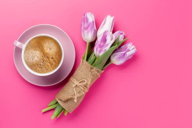 Mor lale çiçekleri ve pembe arka planda kahve fincanı. Kopyalama alanı olan düz