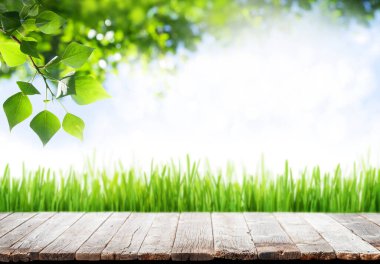 Ürünün için fotokopi alanı olan ahşap masa ve yeşil güneşli bokeh. Açık hava şablonu