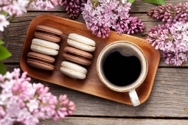 Kurabiye ve kahve. Üzerinde leylak çiçekleri olan ahşap bir masada. Üst görünüm düzlüğü