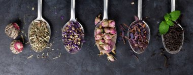 Taş masadaki kaşıklarda çay çeşitleri. Düz yatıyordu