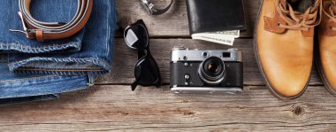 Erkek kıyafetleri ve aksesuarları. Kot pantolon, ayakkabı, gözlük, ahşap arka planda kamera. Üst görünüm düzlüğü