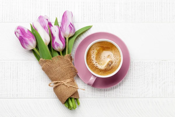 Purple tulip flowers bouquet and coffee cup on wooden table. Flat lay