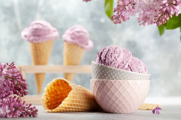 Berry ice cream sundae in waffle cones and lilac flowers