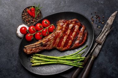 Orta pişmiş Tomahawk bifteği ve kuşkonmaz. Düz yatıyordu