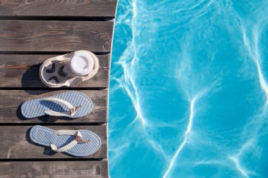 Yüzme havuzunun yanında parmak arası terlik ve kahve. Yaz tatili. Düz yatıyordu