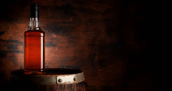 Bottle of whiskey on the old barrel. With copy space on wooden background