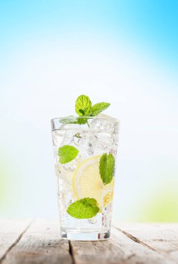 Mojito kokteyli güneşli arka plandaki ahşap masada.