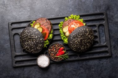 Siyah çöreklerle ev yapımı sığır eti burgeri. Düz yatıyordu