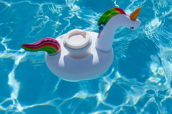 スイミングプールで膨脹可能なユニコーンのおもちゃでカップを飲む 夏休み 休日のコンセプト — ストック写真