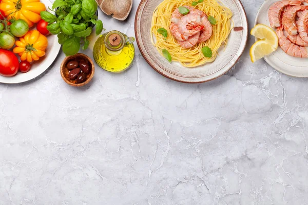 Pasta with shrimps and various garden tomatoes. Italian cuisine. Flat lay with copy space