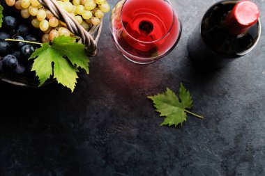 Şarap bardakları, şişeler ve üzümler sepette. Kopyalama alanı olan düz