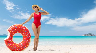 Beautiful young woman with inflatable donut ring relaxing on sea beach. Summer vacation. With copy space