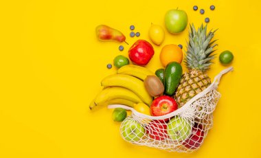 Sarı arka planda sağlıklı meyve dolu alışveriş torbası. Kopyalama alanı olan düz