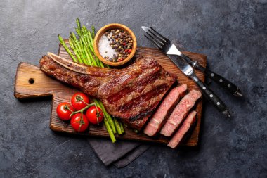 Orta pişmiş Tomahawk bifteği ve kuşkonmaz. Düz yatıyordu