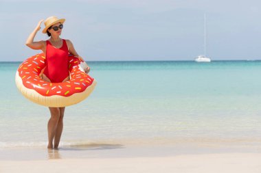 Beautiful young woman with inflatable donut ring relaxing on sea beach. Summer vacation. With copy space