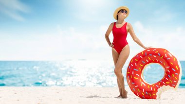 Beautiful young woman with inflatable donut ring relaxing on sea beach. Summer vacation. With copy space