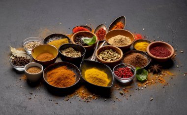 Various spices in bowls and spoons on stone table