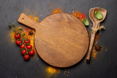 Empty cutting board over various spices on stone table. Frame with copy space for your menu or recipe