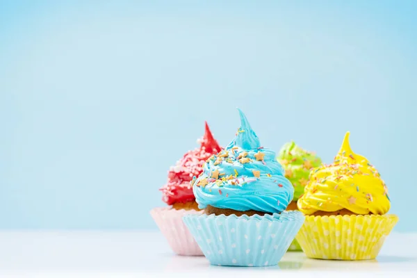 Colorful cupcakes on blue background with copy space