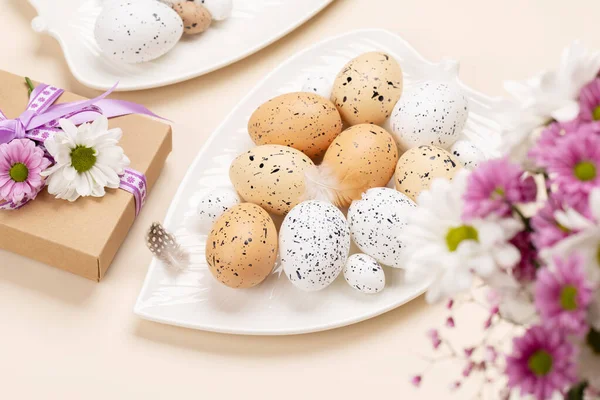プレート上のイースターの卵と花とベージュの背景上のギフトボックス — ストック写真