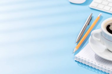 Üst düzey ofis masası, klavye, ofis malzemeleri ve kahve. Güneşli ışıklı çalışma alanı ve kopyalama alanı