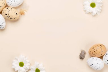 Easter eggs and flowers on a beige background with space for your greetings. Flat lay