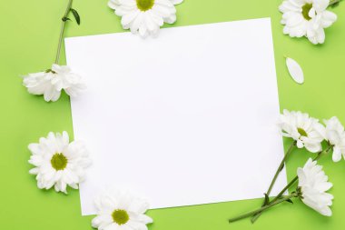 White daisy flowers. Flat lay on green background with blank greeting card for copy space