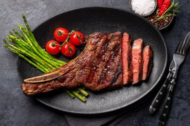 Orta pişmiş Tomahawk bifteği ve kuşkonmaz. Düz yatıyordu