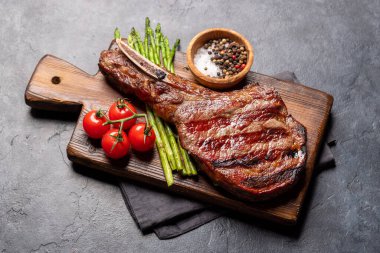 Medium rare grilled Tomahawk beef steak with asparagus on board