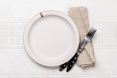 Empty plate with fork and knife on white wooden table. Flat lay with copy space