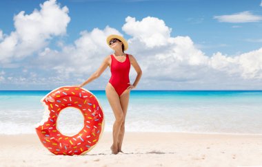 Beautiful young woman with inflatable donut ring relaxing on sea beach. Summer vacation. With copy space