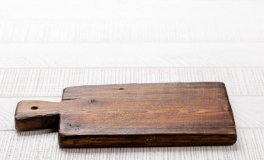 Wooden cutting board on white kitchen table. With copy space