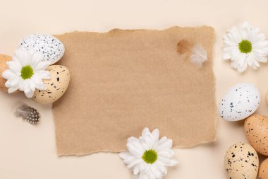 Easter eggs and flowers on a beige background with space for your greetings. Flat lay