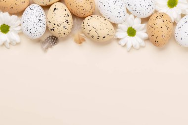 Easter eggs and flowers on a beige background with space for your greetings. Flat lay